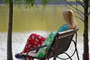Woman sitting on a bench next to a lake. The Truth about taking a break, quitting, and walking away.
