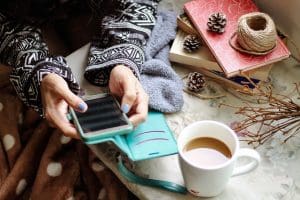 Woman typing on a phone next to a cup of coffee. The Hidden Impact of Social Media on The Home