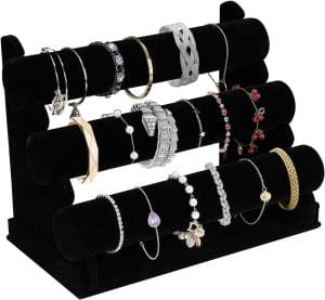 A stand with 3 horizontal bars made of velvet to hold bracelets. The bars are stacked on top of each other and slightly behind one another as the stand ascends.