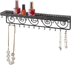A small metal shelf which has 3 bottles of nail polish on the shelf, and cup hooks along the bottom for holding necklaces and bracelets.