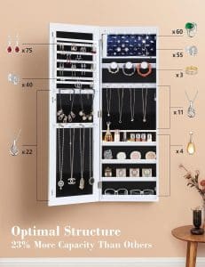 A white, wall-mounted cabinet with black interior. The door is open and there are hooks and shelves inside, along with measurements. It is filled with jewelry.