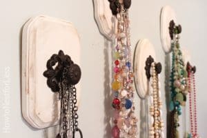 Decorative Knobs that have been attached to painted wooden backings (like small plaques) and from which jewelry is being hung.