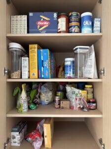 Pantry shelves before being organized. Items are crowded and some are on their sides.