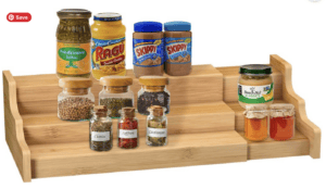 Bamboo expandable shelf with three levels holding peanut buttter, pasta sauce, and spices.
